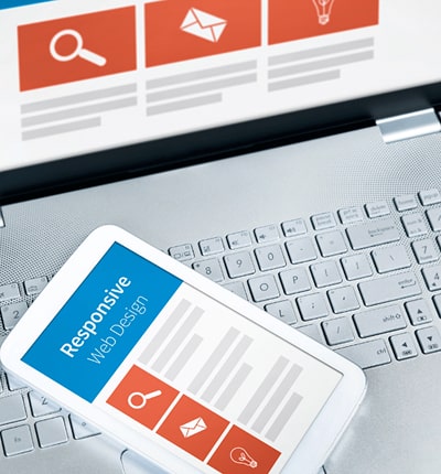 Close-up of a phone lying on a laptop keyboard. Both the phone and laptop screens display text that 