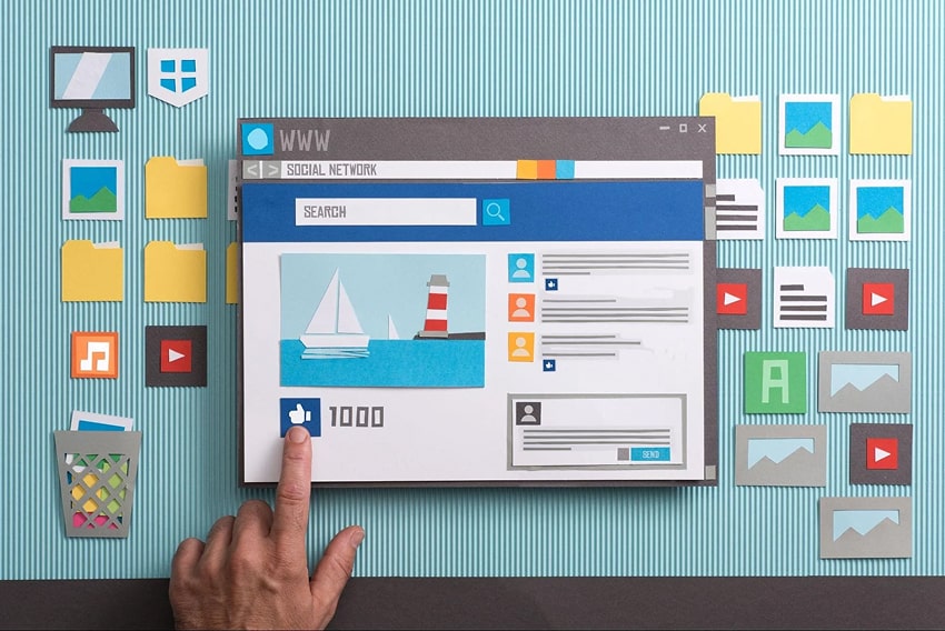 A computer workspace with icons made out of paper, social media page open and person liking a pictur
