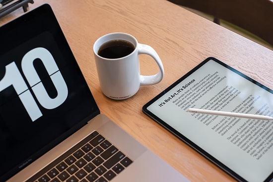 Laptop, tablet and a cup of coffee on a desk. 